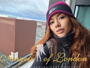 London escort Makani in coat and hat