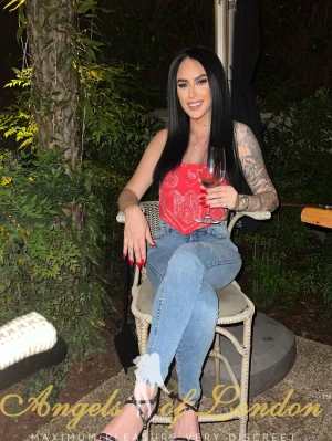 London escort Zari sitting outdoors in jeans