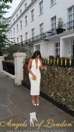 London escort Tissa on the street in white dress
