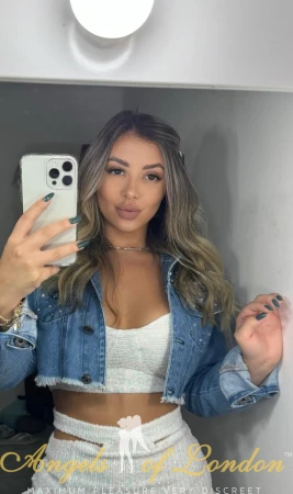 London escort Petunia in open jacket showing bra