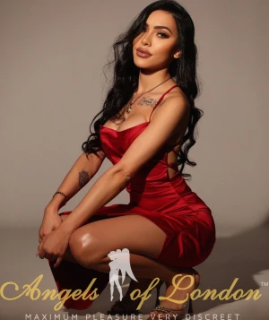 London escort Nomira crouching in red dress