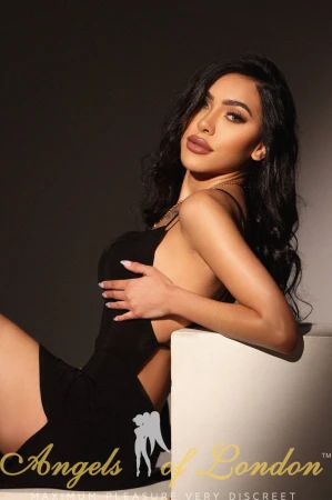 London escort Nomira sitting in black dress